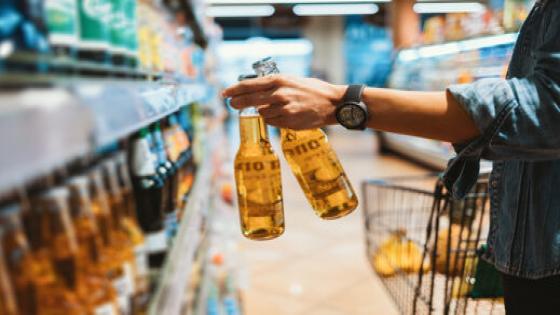 Close-up of female hand holding two glass bottle with alcoholic drink in store